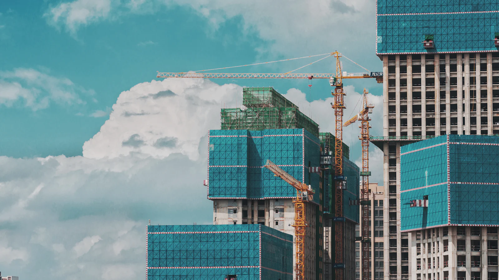 Glass-clad commercial towers under construction with tower cranes