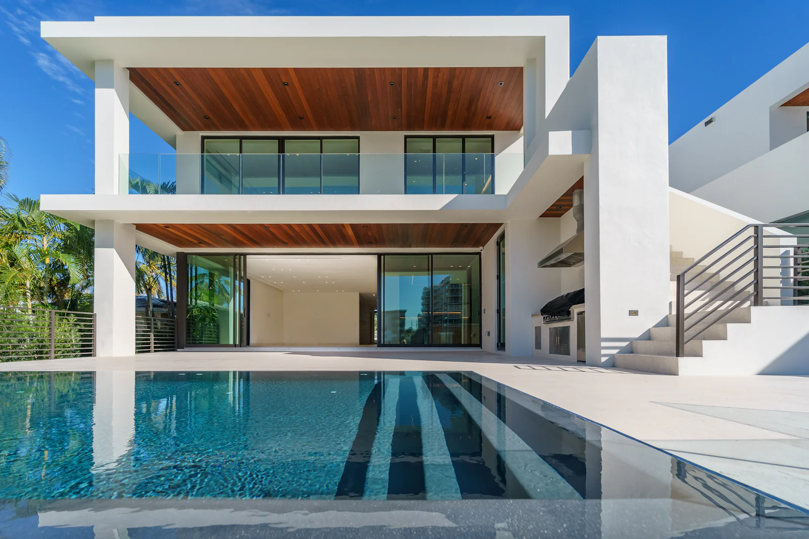 White contemporary villa with a timber-lined canopy and reflecting pool