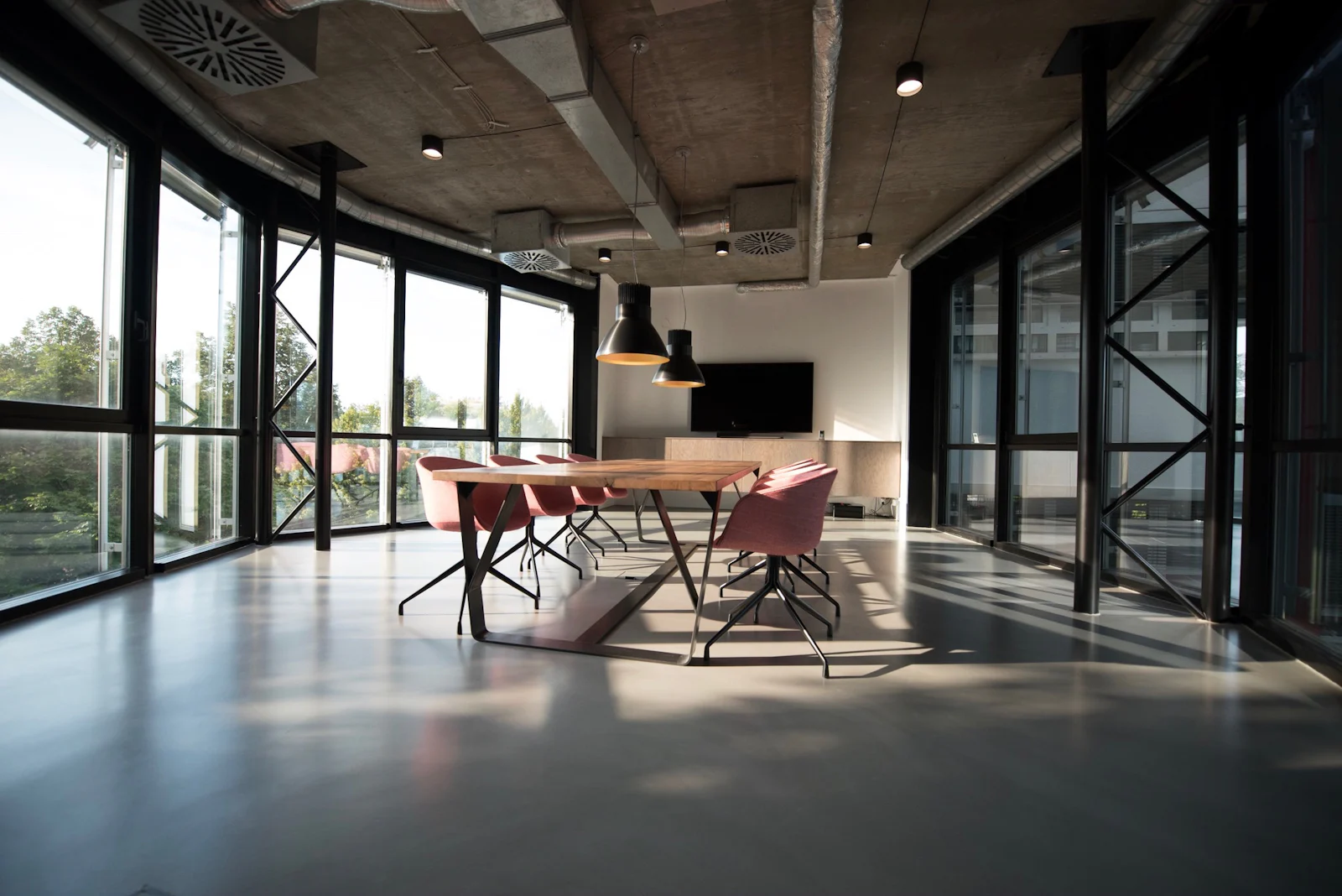 Open-plan office interior with exposed ceiling, glass partitions and meeting table