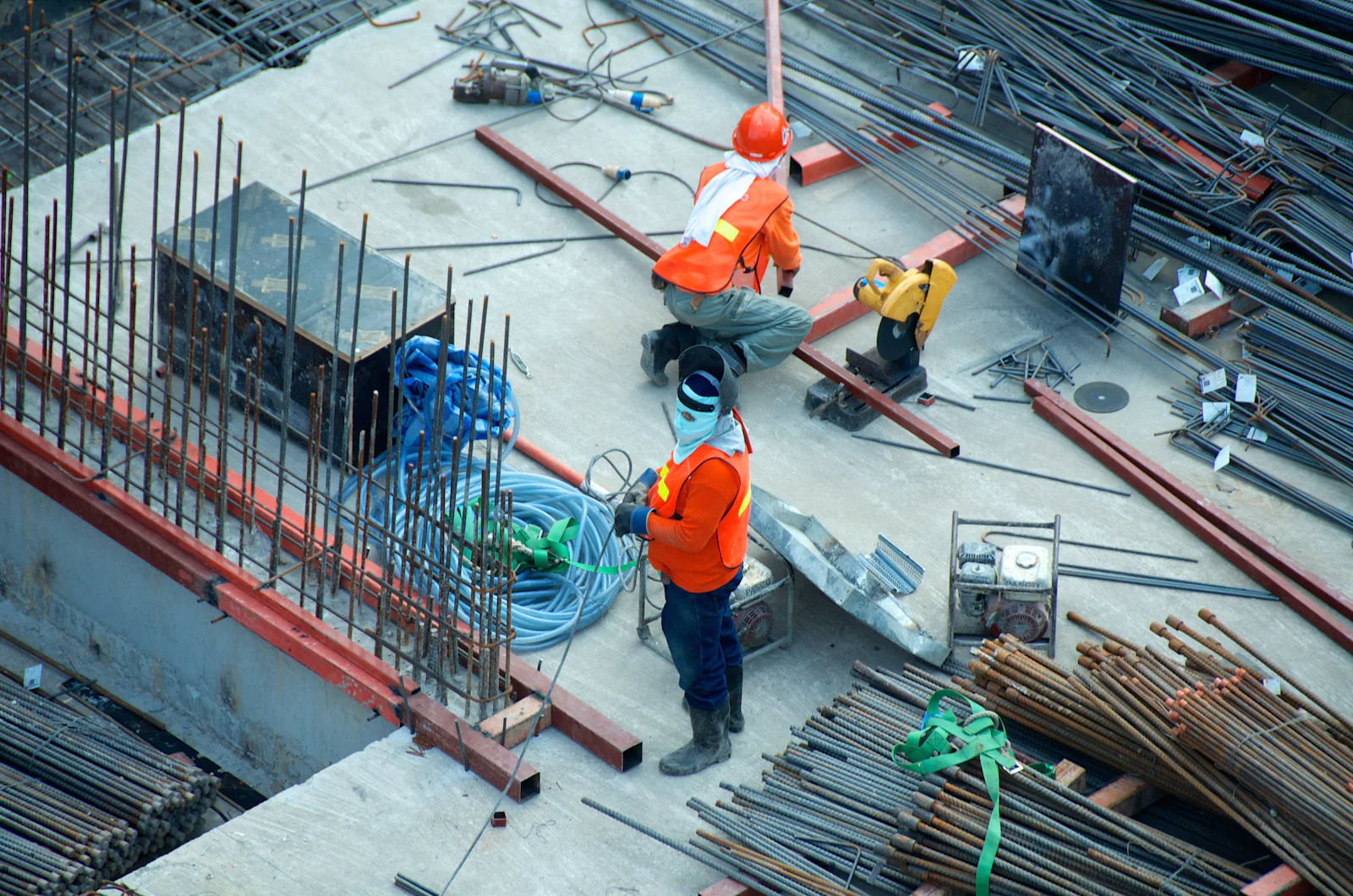 Construction workers in hard hats and hi-vis vests tying steel reinforcement on a building deck