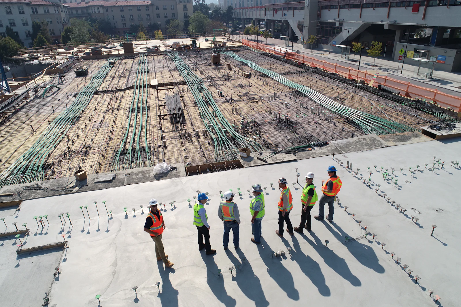 Site engineers in safety gear reviewing a large concrete slab on an active construction site